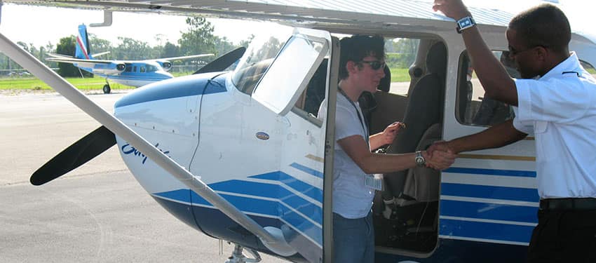 students shake hands by an airplane